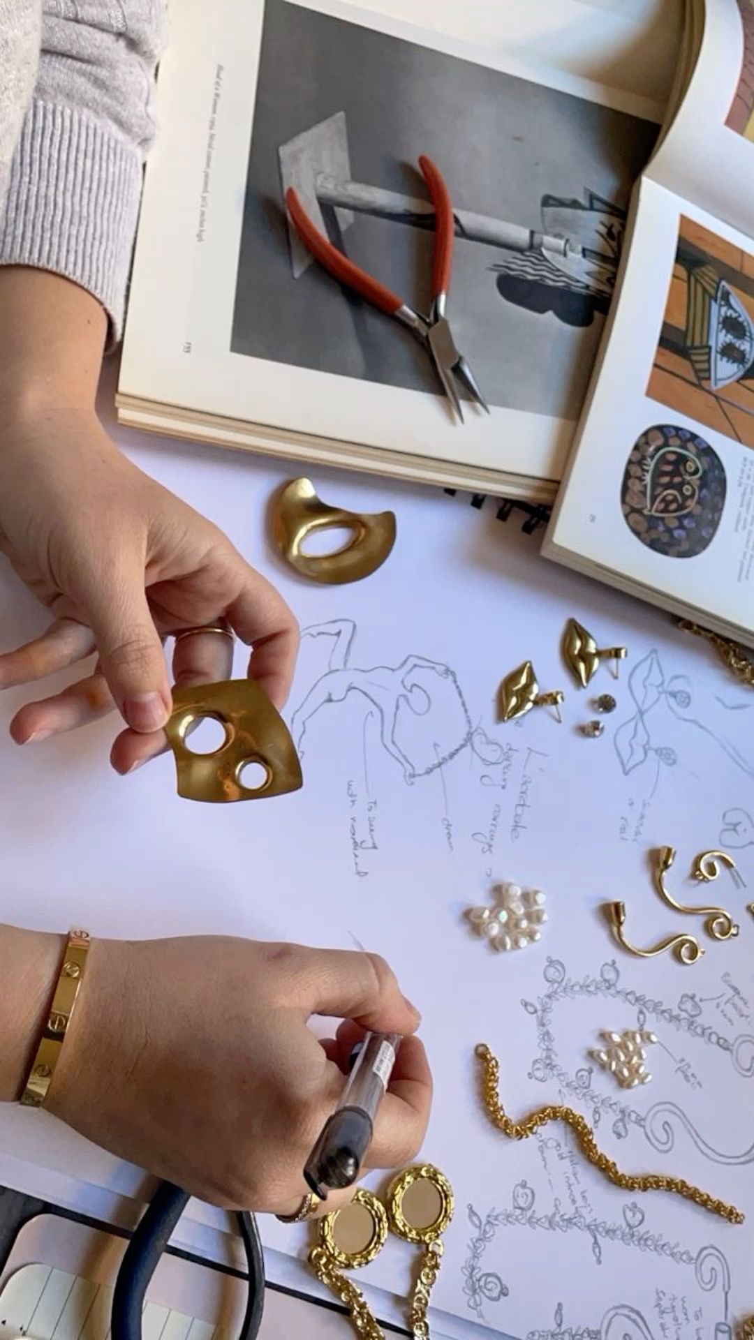 Designer at work sketching jewellery pieces with brass and gold components